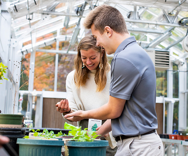 student and teacher gardening in the campus greenhouse