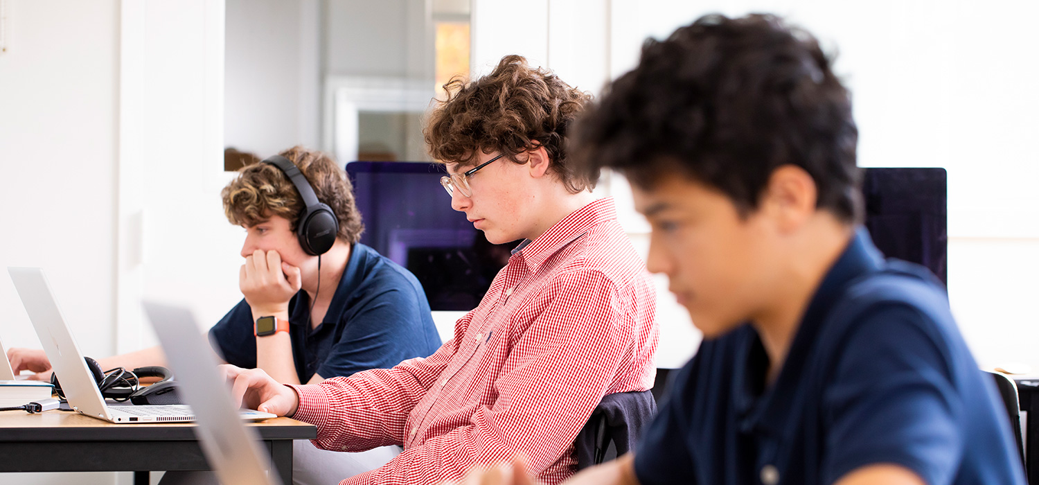 3 students working on computers in class